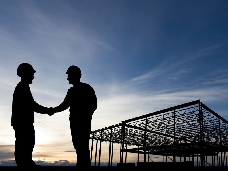 Business partnership handshake at industrial facility