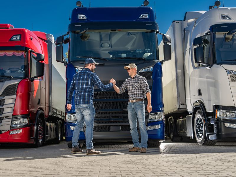 Two truck drivers standing in front of semi trucks – commercial truck insurance coverage